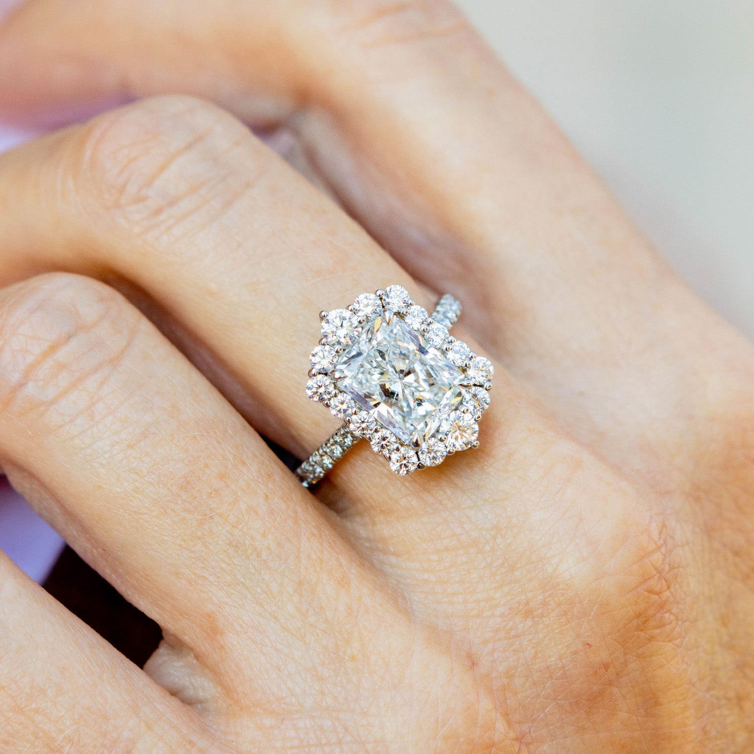 Diamond ring on a person's finger with a neutral background