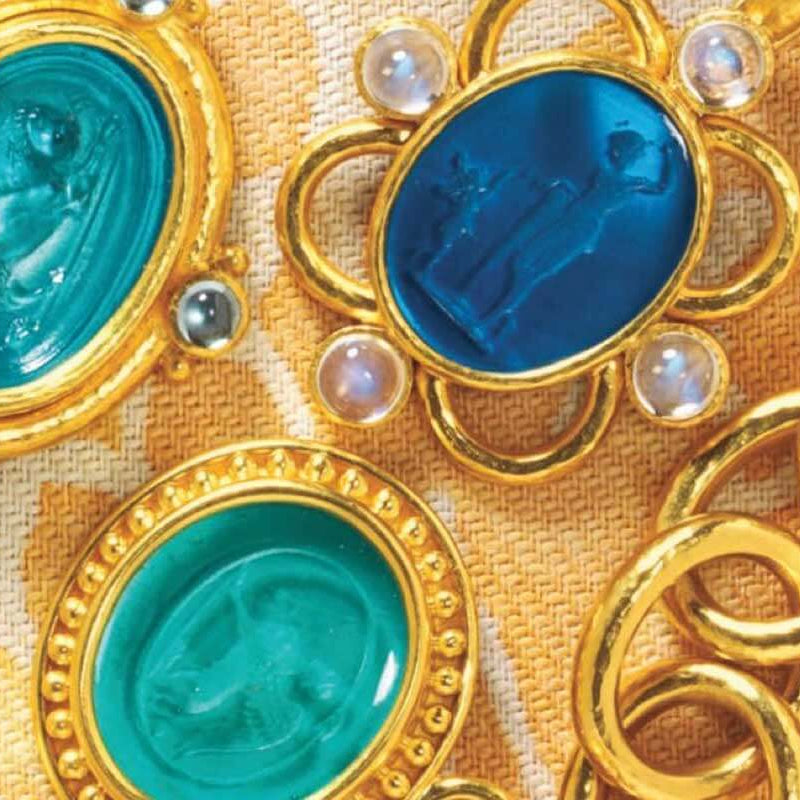 Close-up of gold jewelry with blue gemstones on a textured fabric background