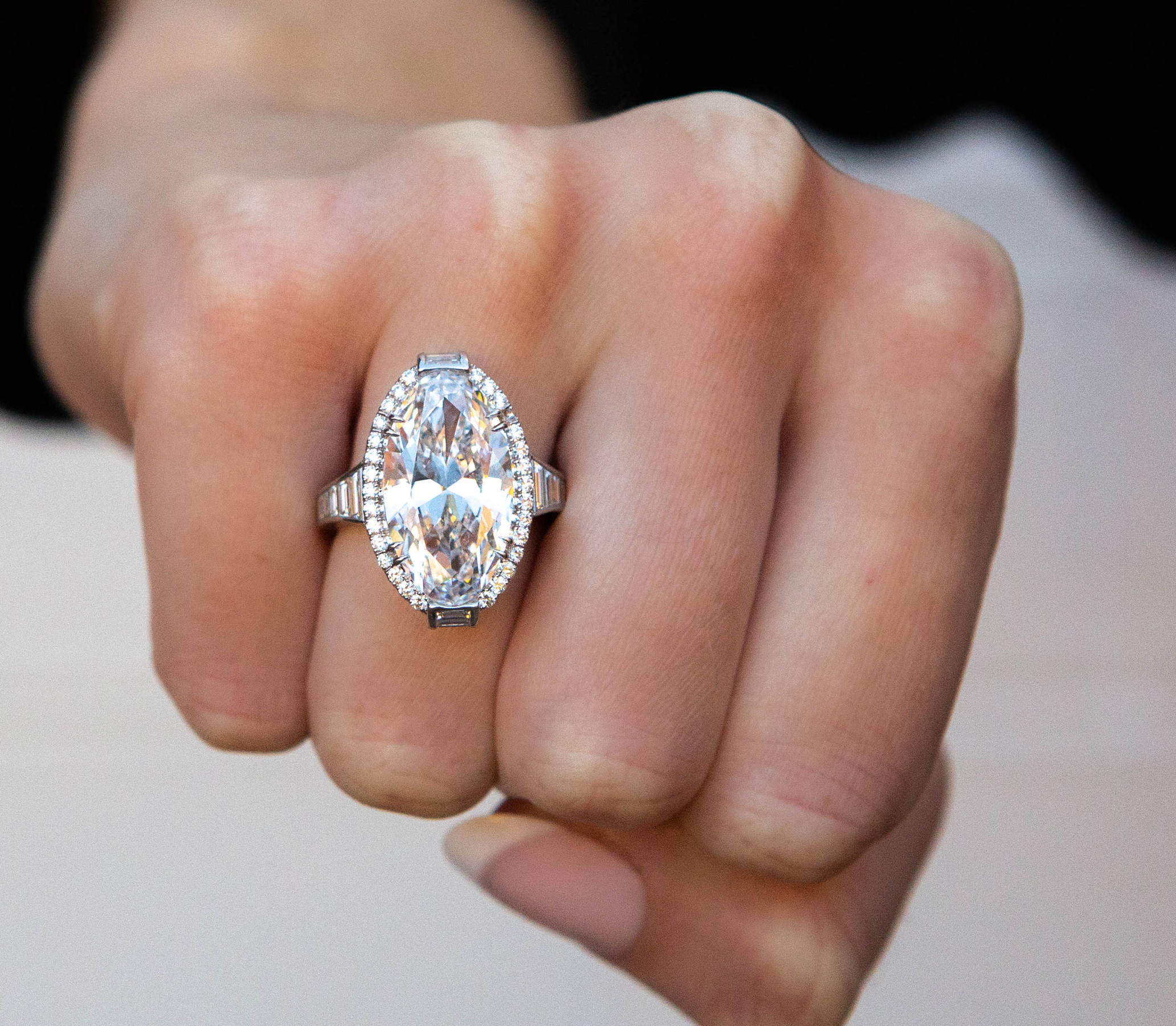 Close-up of a hand wearing a diamond ring with a blurred background