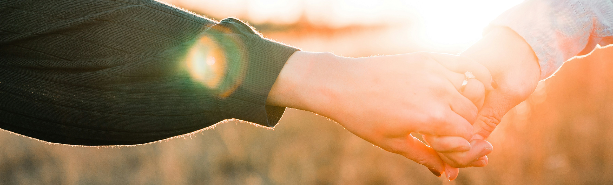 Two people holding hands with a warm, blurred background