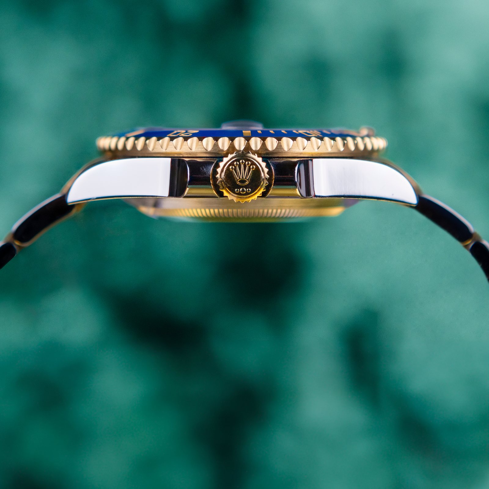 Close-up of a gold watch with a blurred green background
