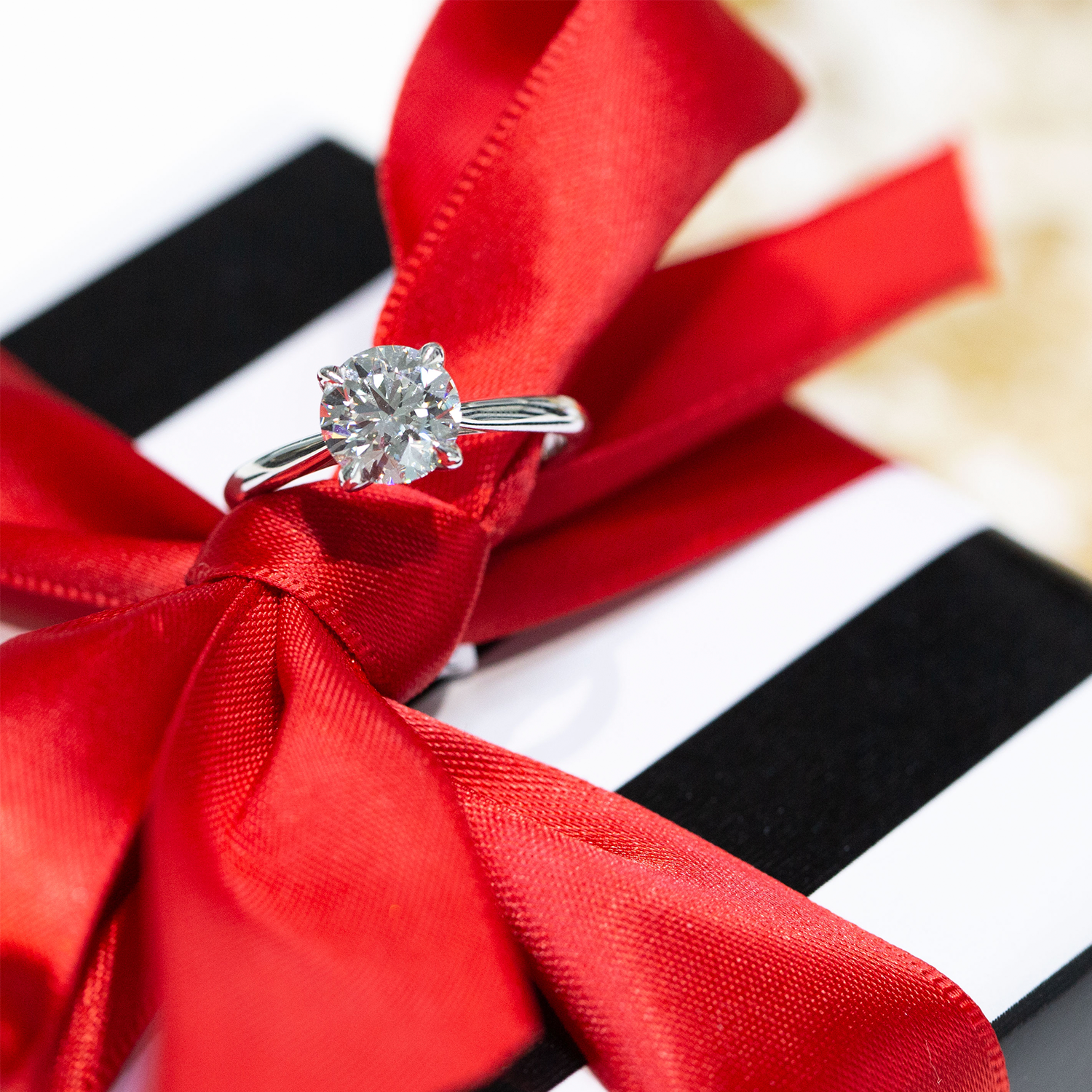 Diamond ring on a red ribbon with a white and black striped background