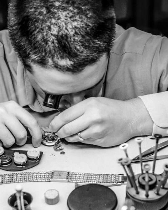 Person working on a small mechanical object with tools on a table